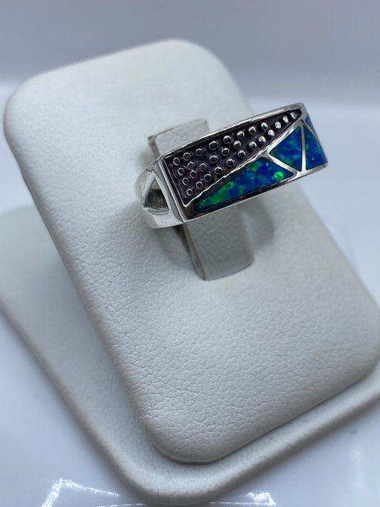 Detalle lateral del anillo mostrando la textura artesanal y el juego de color azul-verde del ópalo