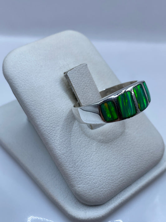 Vista frontal del anillo con ópalo de fuego mostrando reflejos verde limón y amarillo