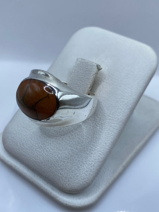 Detalle lateral del anillo mostrando el engaste a mano de la piedra café