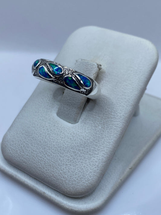 Anillo de ópalo azul en dedo, mostrando el juego de color natural de la piedra