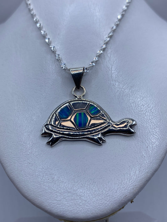 Tortuga de plata en primer plano mostrando el ópalo de fuego incrustado en tonos azul y verde