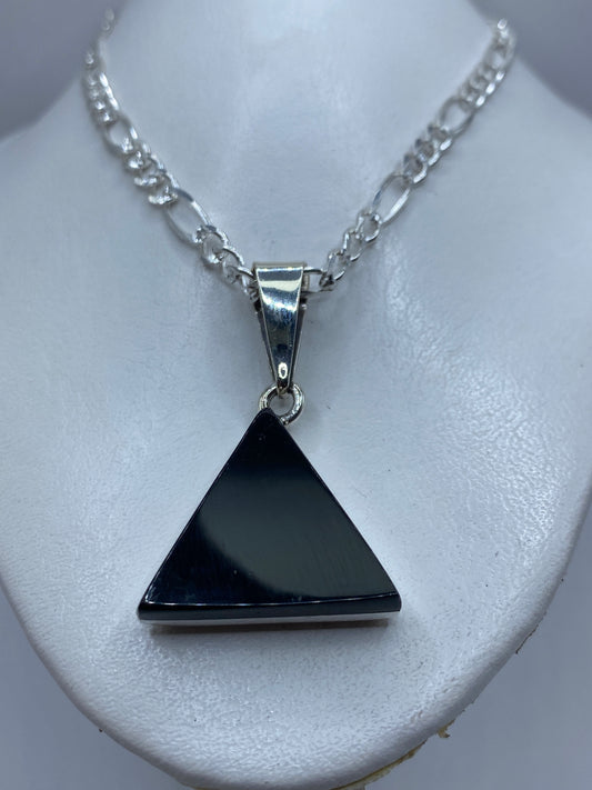 Detalle del ónix negro pulido y el engaste de plata en el dije triangular