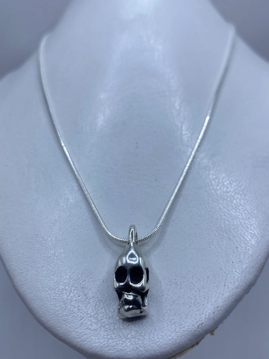 Vista frontal del dije calavera minimalista en plata pulida