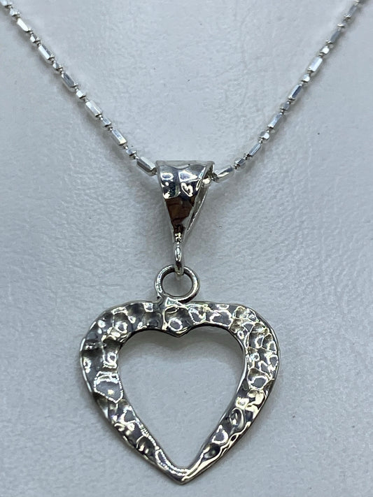 Detalle del corazón abierto en plata .925 mostrando el acabado combinado pulido