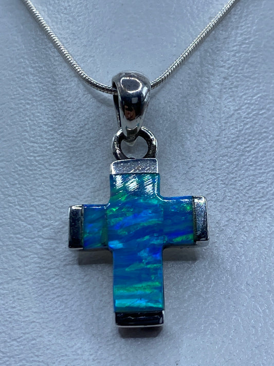 Detalle frontal del ópalo azul incrustado en la cruz de plata, mostrando reflejos de luz