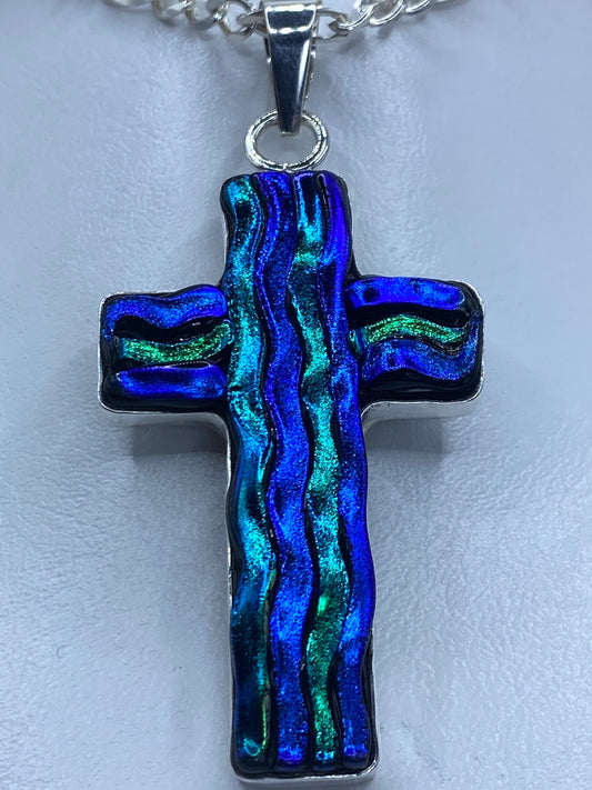 Detalle frontal de la cruz mostrando la incrustación decorativa con destellos azules y verdeazulados