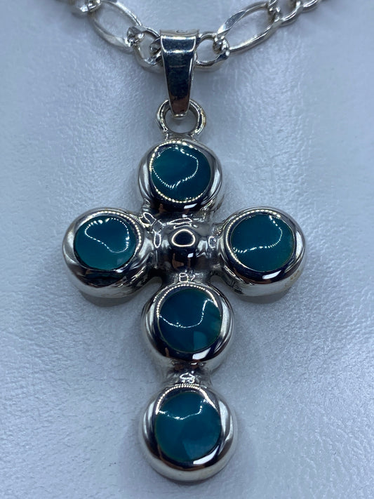 Detalle del engaste a mano de la piedra Ojo de Gato azul en la cruz de plata