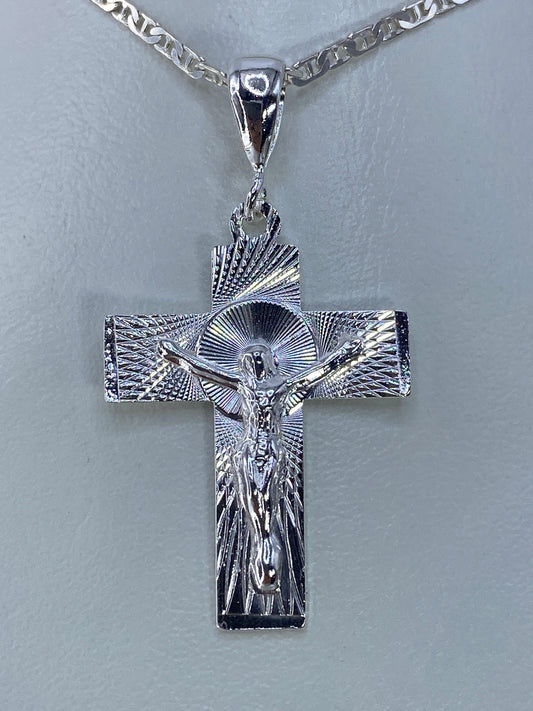 Detalle frontal del Cristo repujado en el dije de cruz