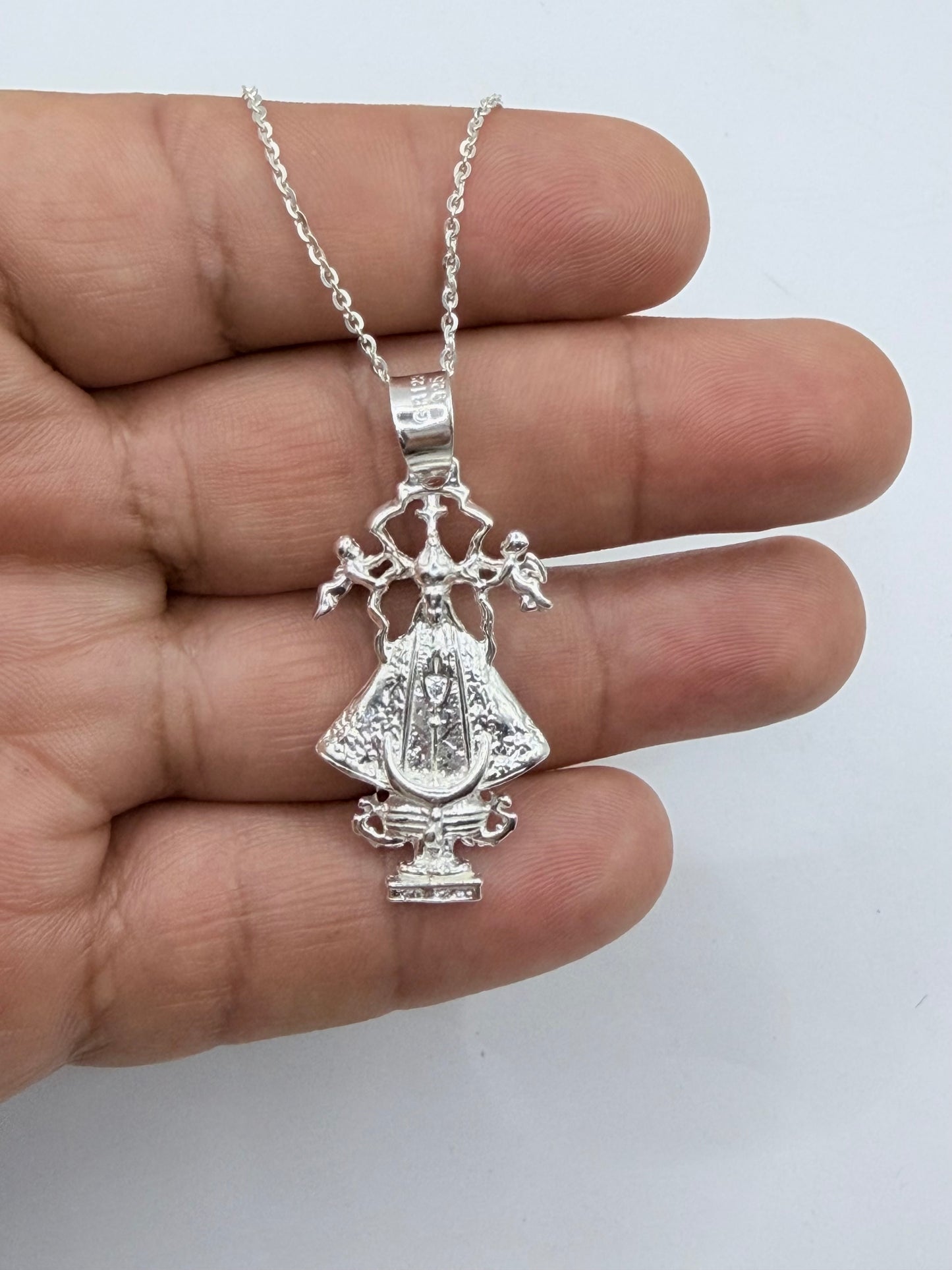 Collar Virgen San Juan de los Lagos en la mano, mostrando proporción y detalles de fundición en plata