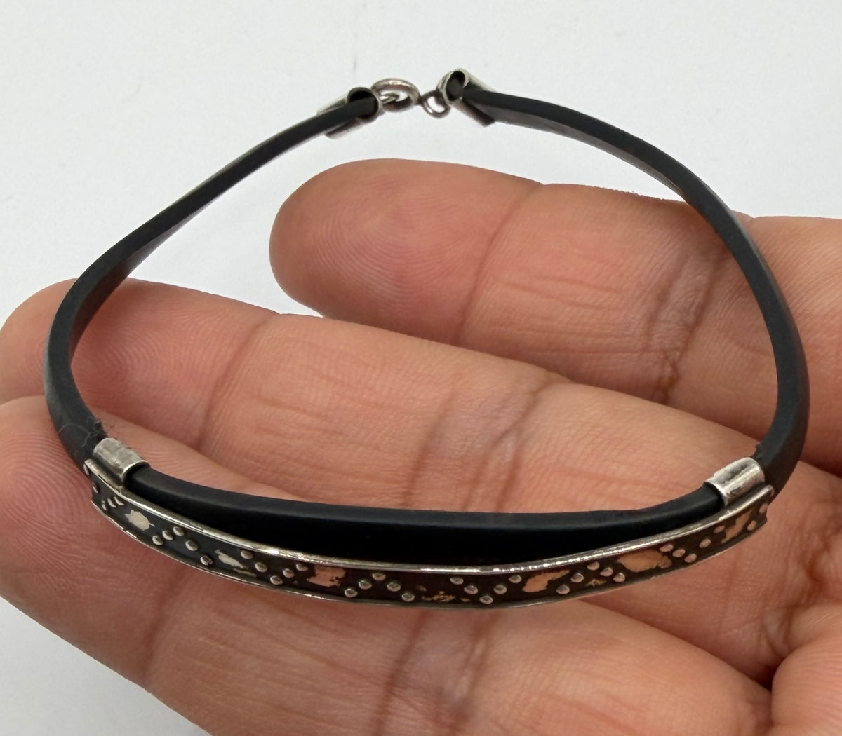 Vista frontal de pulsera de plata y caucho, cierre de gancho visible