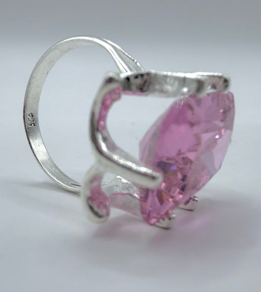 Detalle lateral del anillo mostrando los engastes de circonia rosa y la estructura de plata pulida