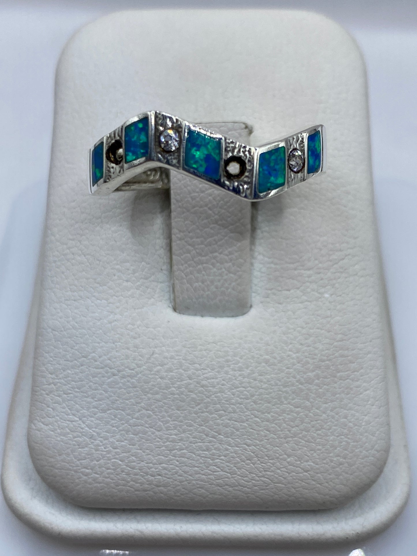 Anillo de plata .950 con ópalo de fuego azul en forma geométrica sobre almohada blanca