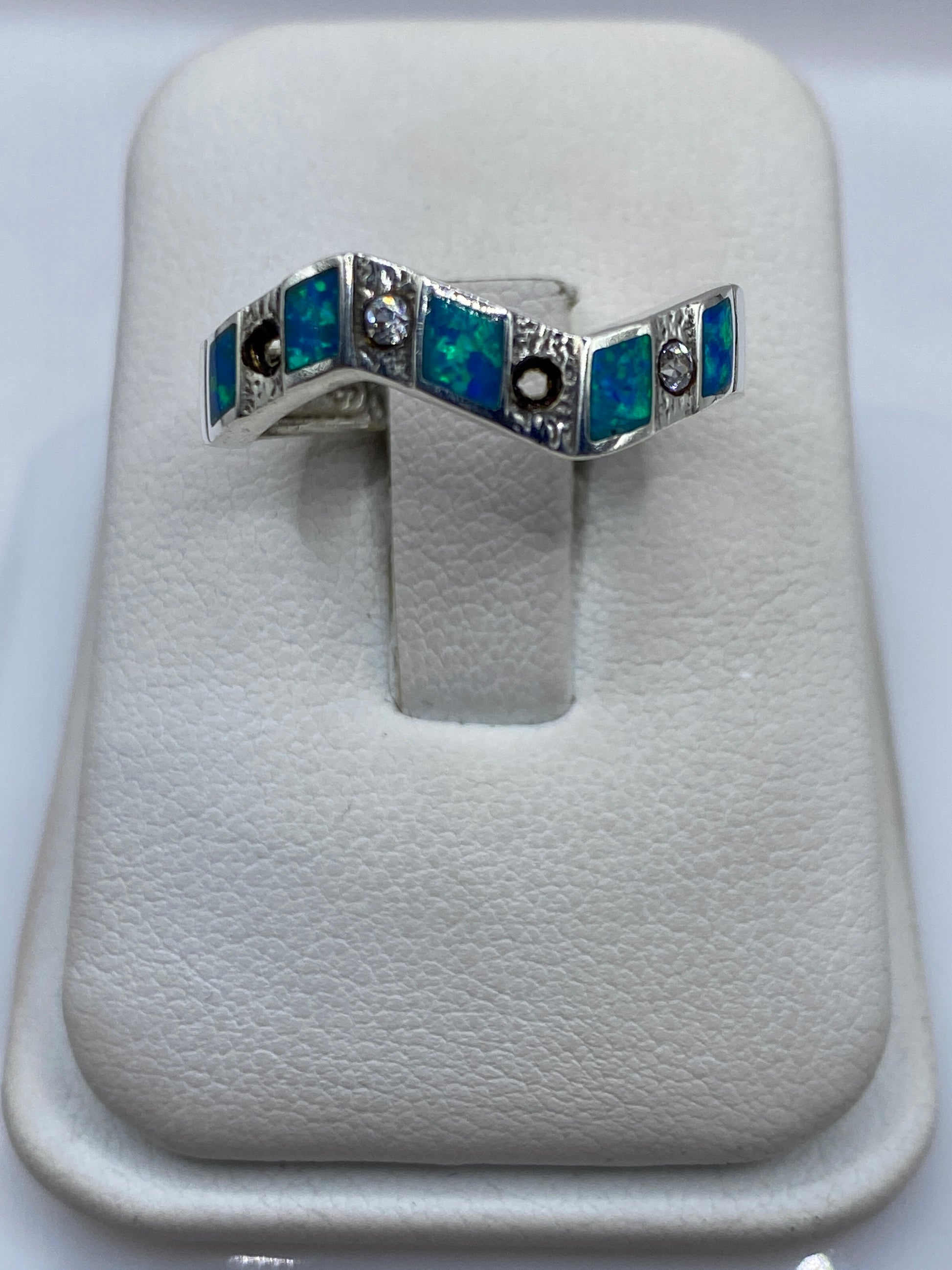 Anillo de plata .950 con ópalo de fuego azul en forma geométrica sobre almohada blanca