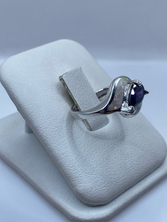 Anillo ópalo de fuego en la mano de una mujer, luz reflejando los colores naturales