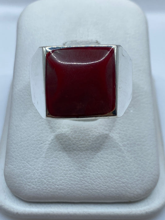 Anillo de plata .925 con sello de coral rojo sobre dedo masculino