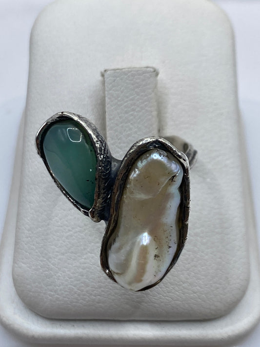Anillo de plata con perla natural blanca en marco geométrico, vista de frente sobre mano