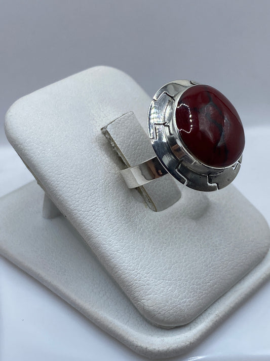 Anillo ajustable de coral rojo en la mano de una mujer, mostrando el brillo natural de la piedra