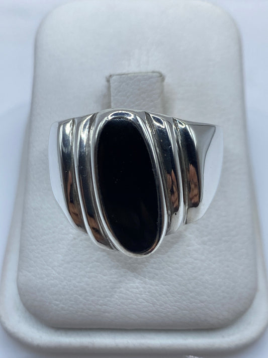 Anillo de plata con ónix negro oval en la mano de un hombre