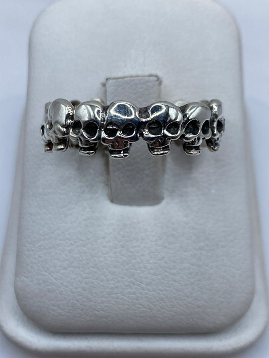 Anillo de plata con calaveras en relieve continuo en dedo de hombre