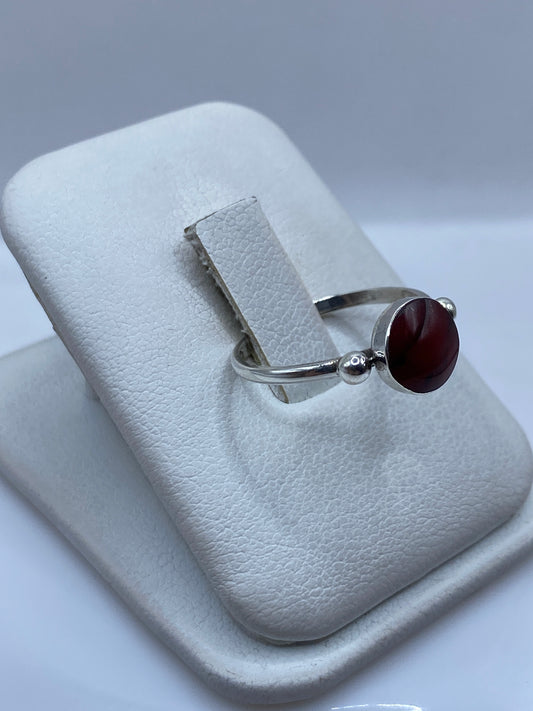 Anillo solitario de coral rojo en plata, fotografiado en perfil mostrando la banda fina