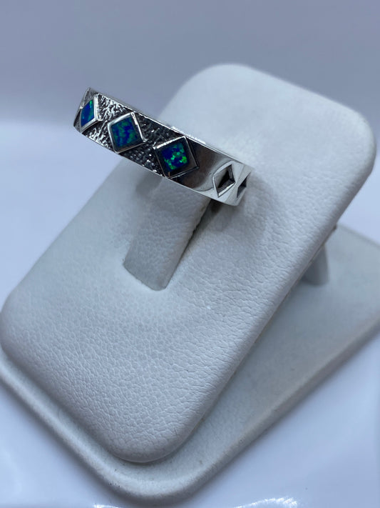 Detalle lateral del anillo mostrando el juego de colores azul y verde del ópalo
