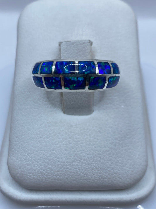 Anillo de plata .950 con ópalo de fuego azul en la mano, mostrando el brillo y fuego natural de la piedra