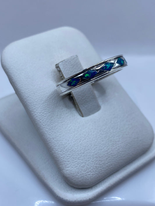 Anillo unisex con ópalo de fuego sobre dedo mostrando los destellos azules naturales