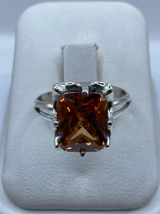 Anillo de plata solitario con circonia ámbar en la mano de una mujer