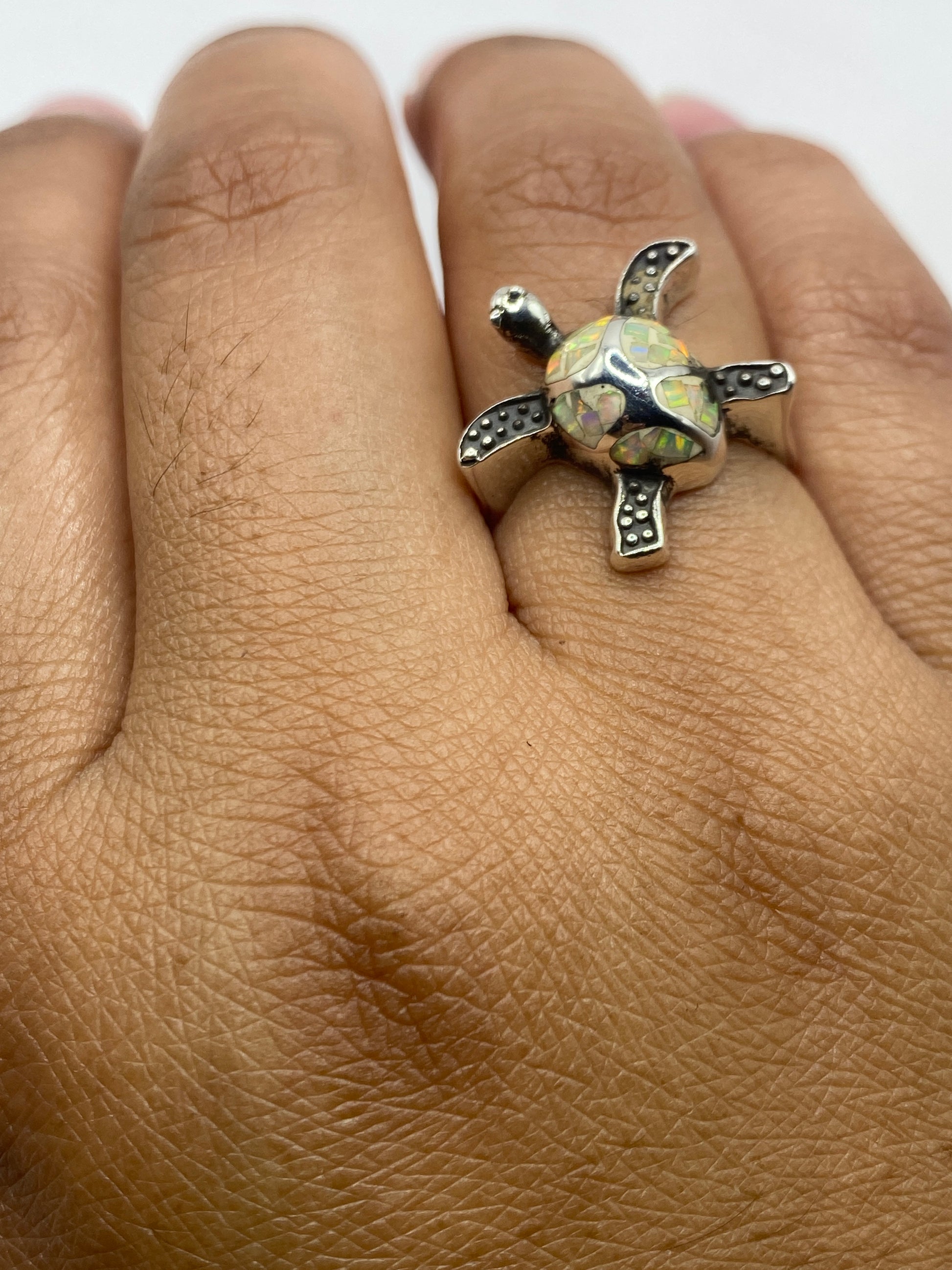 Anillo en mano de mujer luciendo el fuego multicolor del ópalo natural