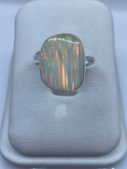 Anillo de plata con ópalo de fuego multicolor en mano de mujer, mostrando reflejos rojo-naranja