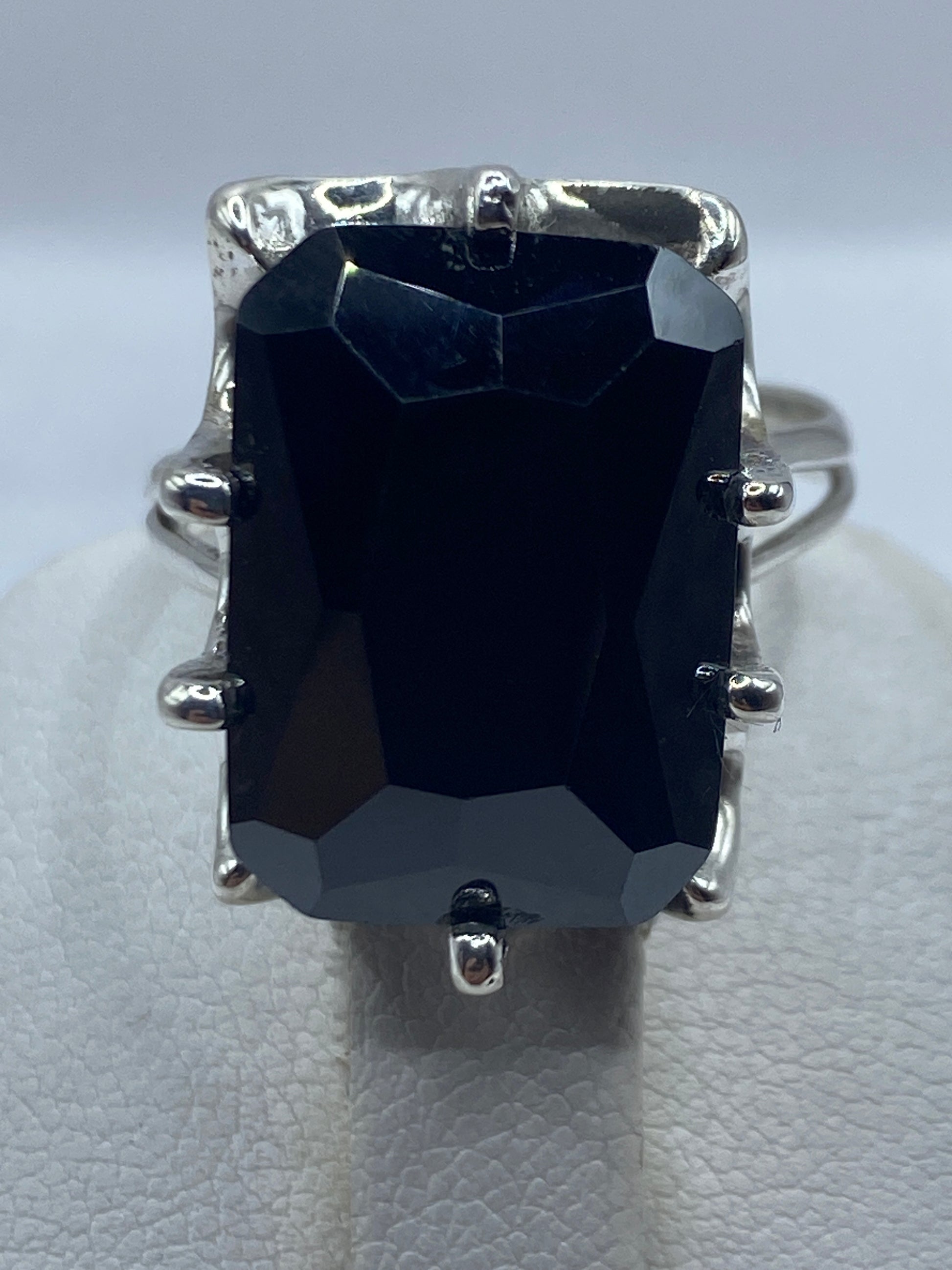 Anillo cocktail negro en la mano de una mujer mostrando brillo y facetas