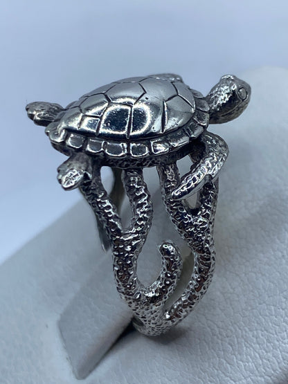 Anillo puesto en dedo índice, vista frontal de las tortugas abrazando la banda