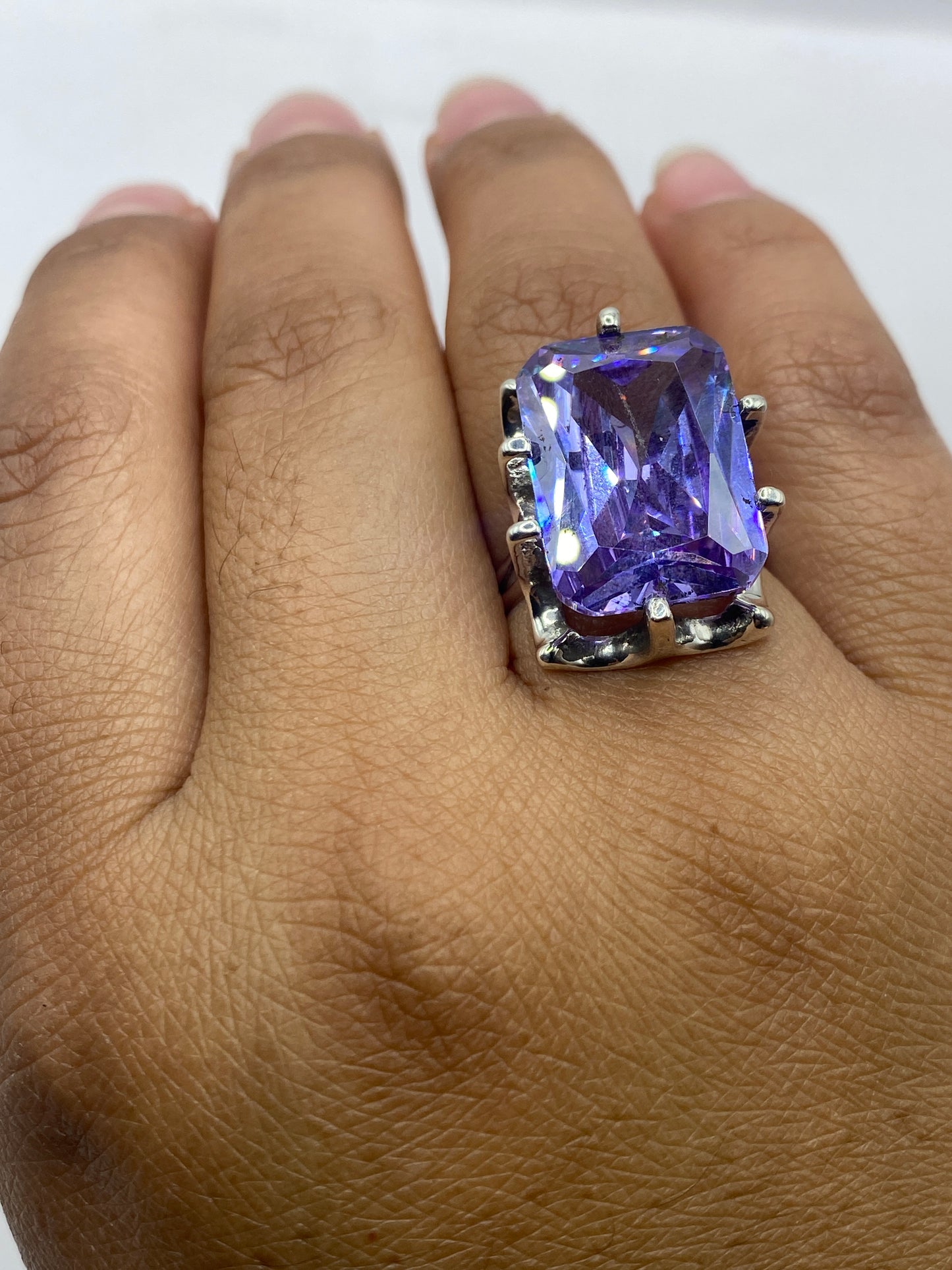 Anillo de plata con sello 925 y circonia morada sobre fondo neutro