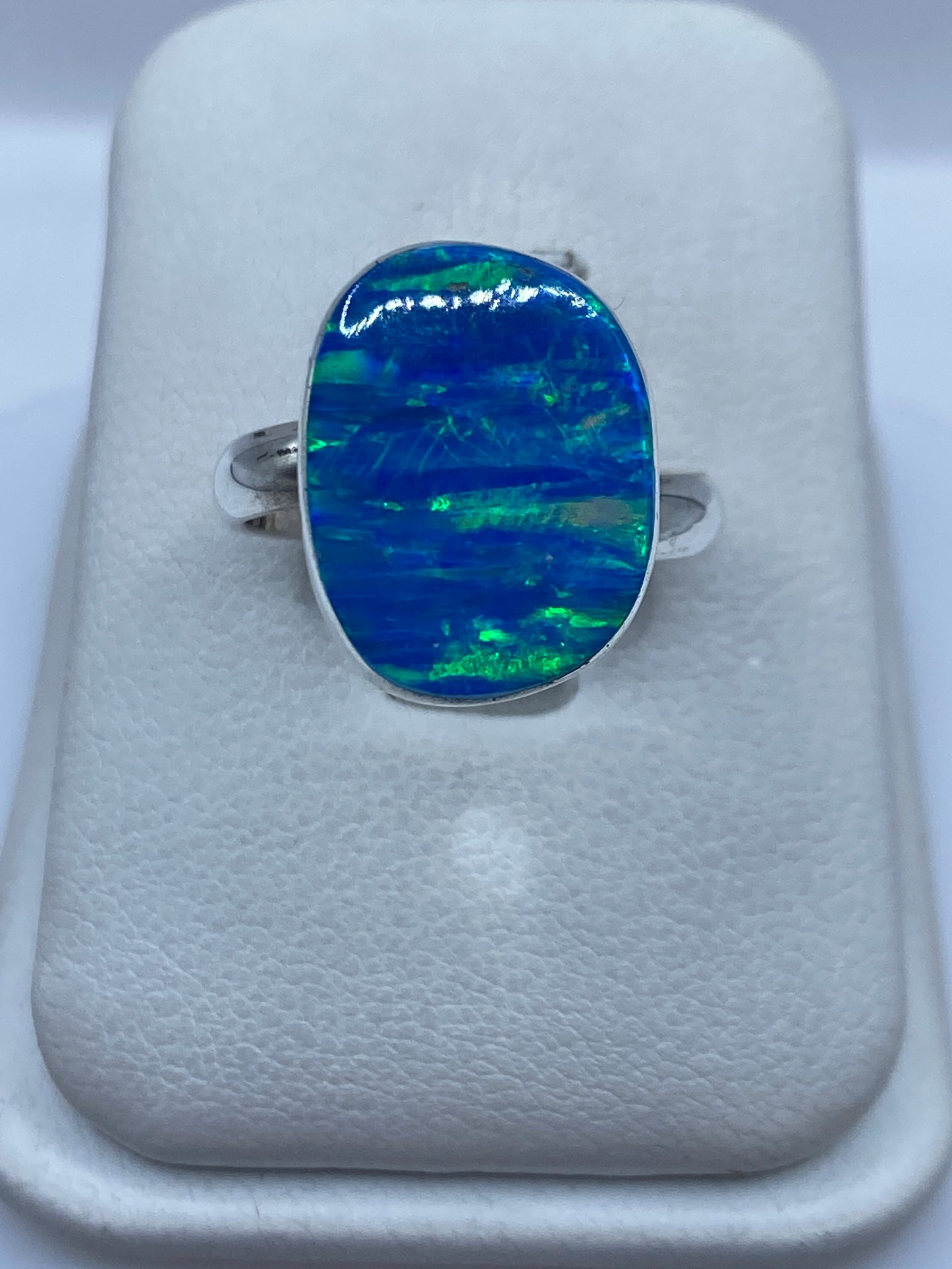 Anillo de plata ajustable con ópalo de fuego azul y verde en la mano de una mujer