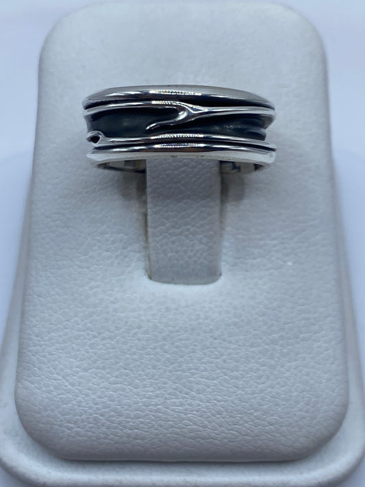 Anillo de plata con bandas superpuestas en los dedos de una persona