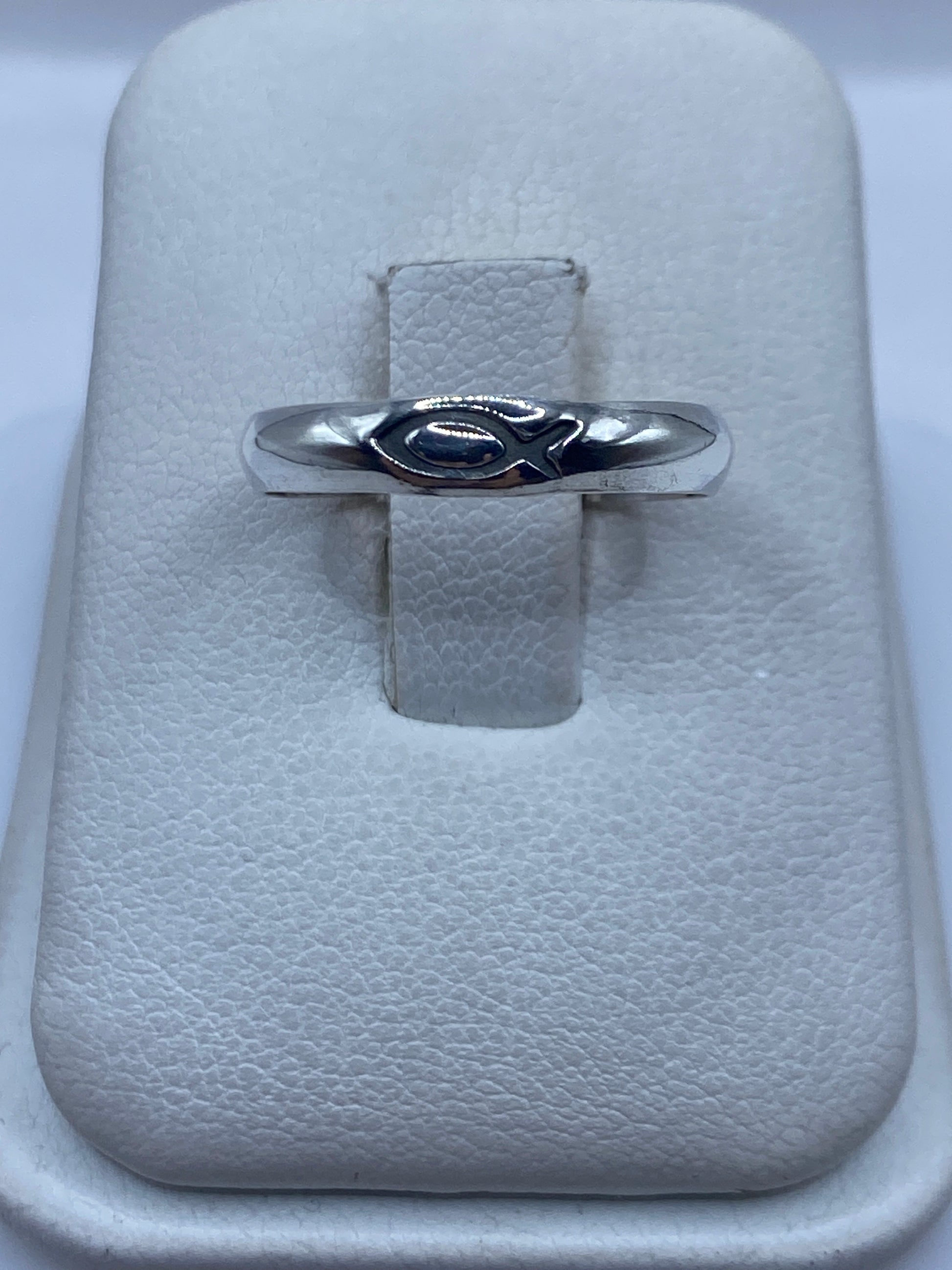Anillo de plata pulida minimalista sobre soporte blanco, vista frontal mostrando el diseño solitario