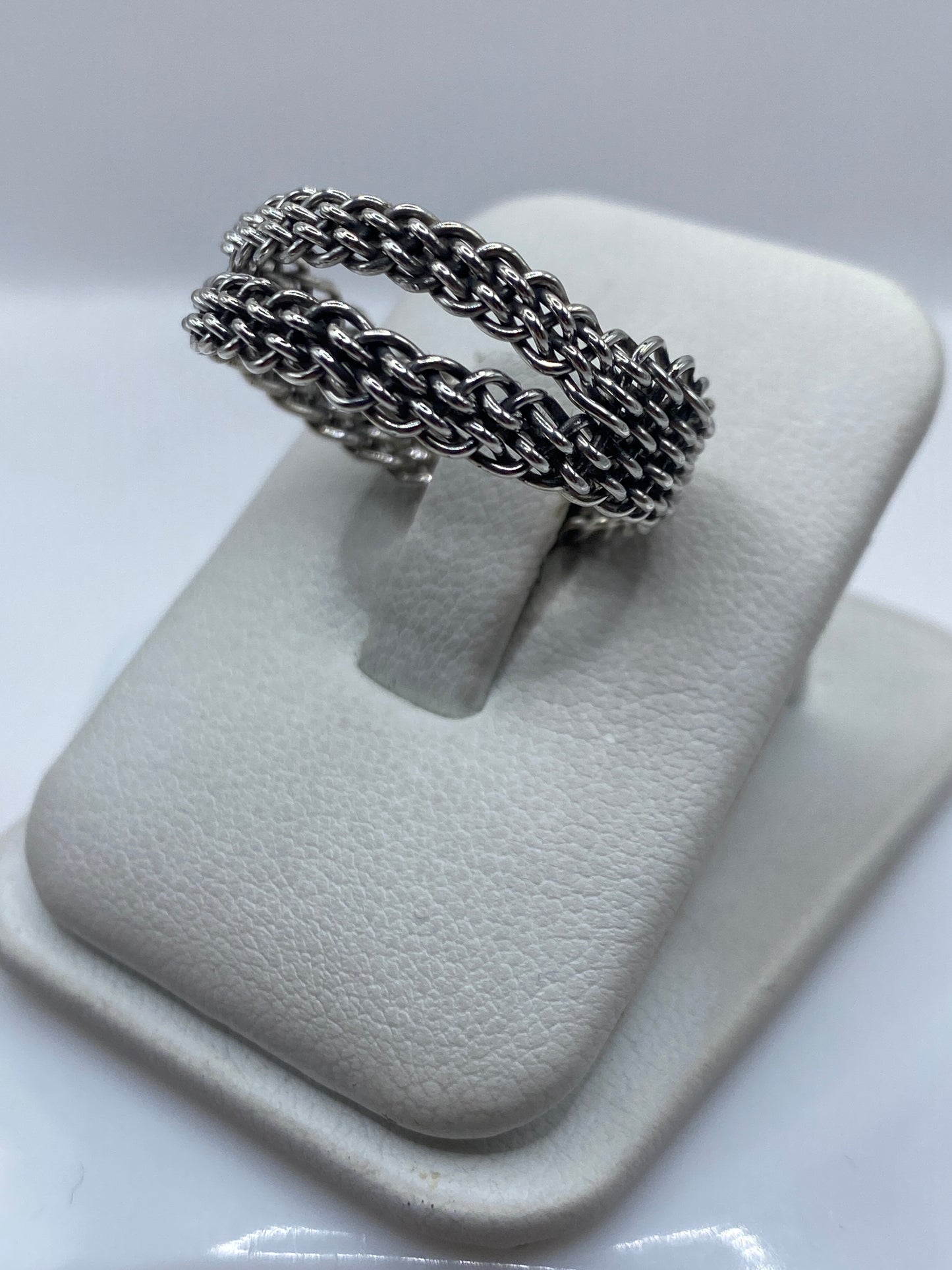 Anillo trenzado en la mano mostrando textura de dos hilos entrelazados