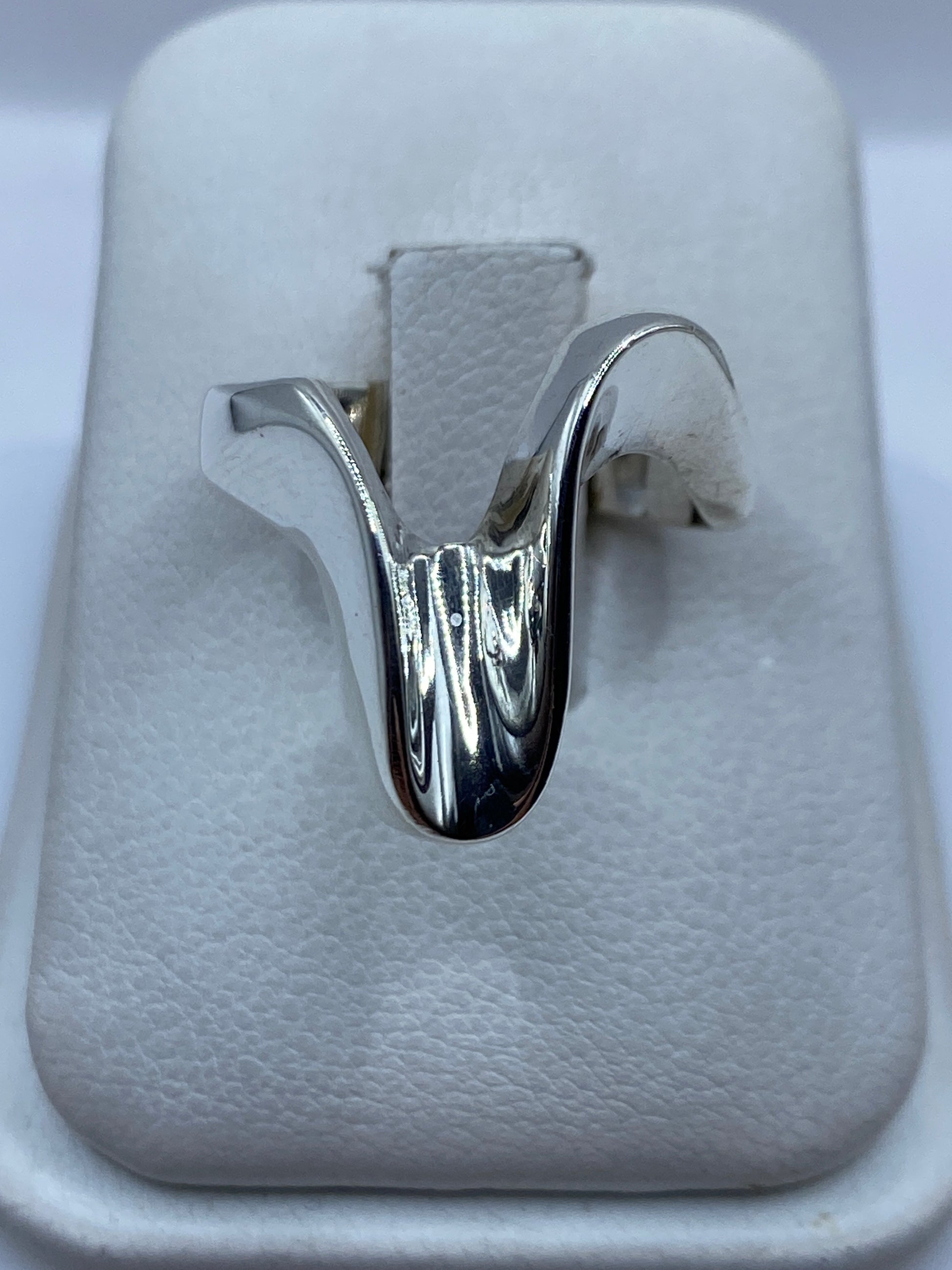 Anillo de plata fluido en forma orgánica, vista frontal sobre el dedo
