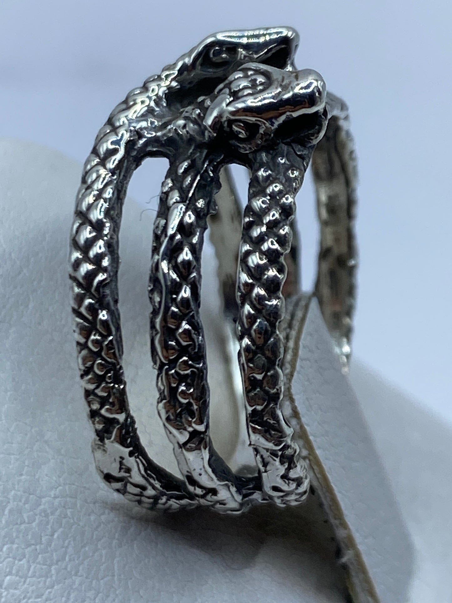 Anillo de serpiente bicéfala en la mano de una persona, mostrando peso y volumen