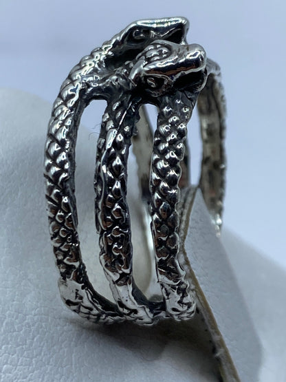 Anillo de serpiente bicéfala en la mano de una persona, mostrando peso y volumen