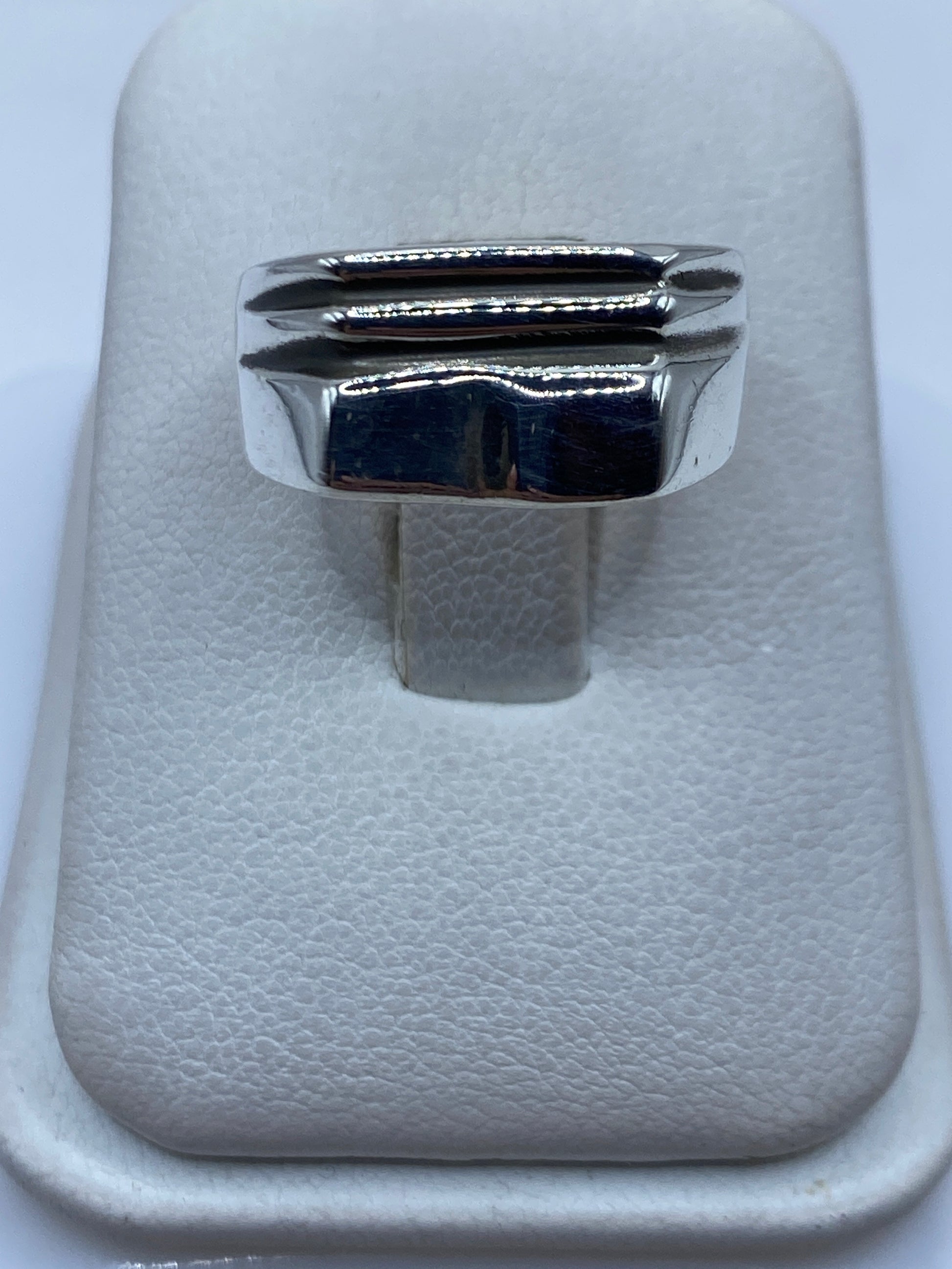 Anillo de plata sello escalonado sobre fondo blanco mostrando diseño geométrico