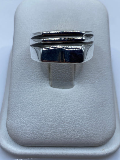 Anillo de plata sello escalonado sobre fondo blanco mostrando diseño geométrico