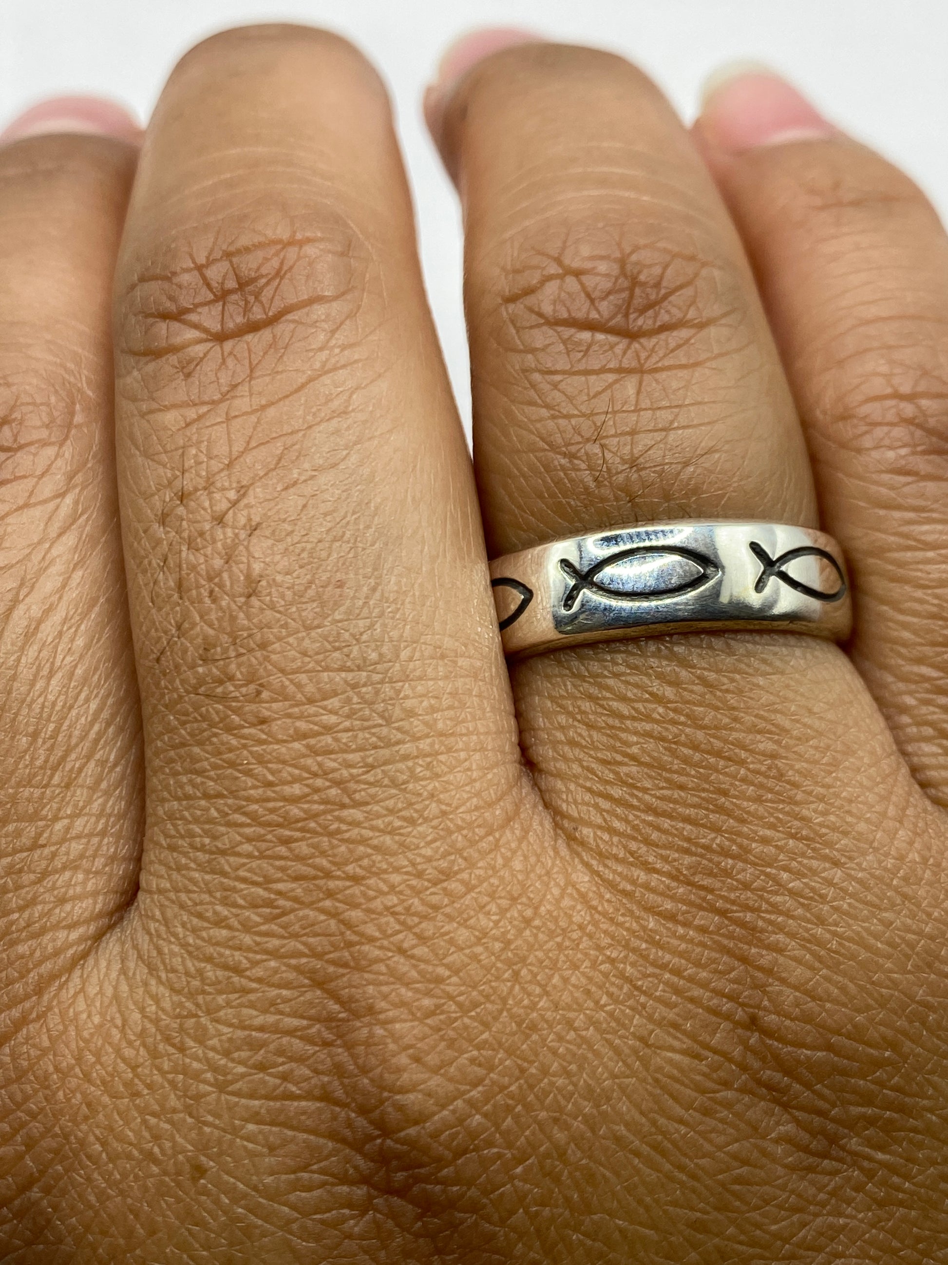 Anillo de peces en la mano mostrando pulido brillante y tallado artesanal