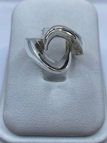 Anillo de plata ondulado minimalista sobre dedo de mujer, diseño fluido
