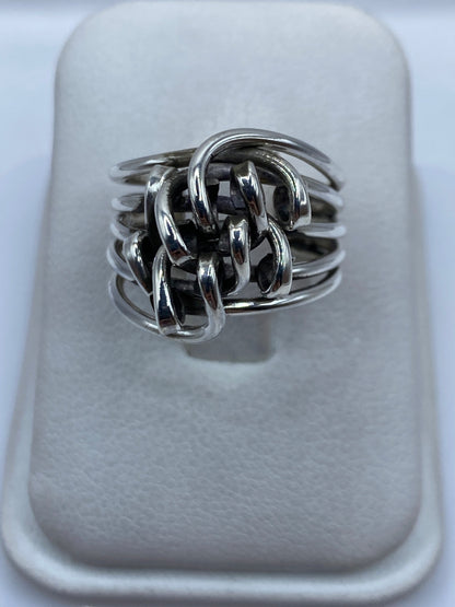 Anillo de plata arquitectónico entrelazado en la mano de una mujer