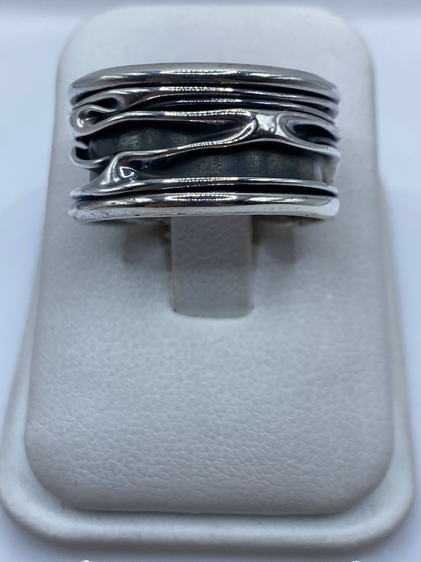 Anillo de plata con bandas fluidas abiertas visto desde arriba en estuche blanco