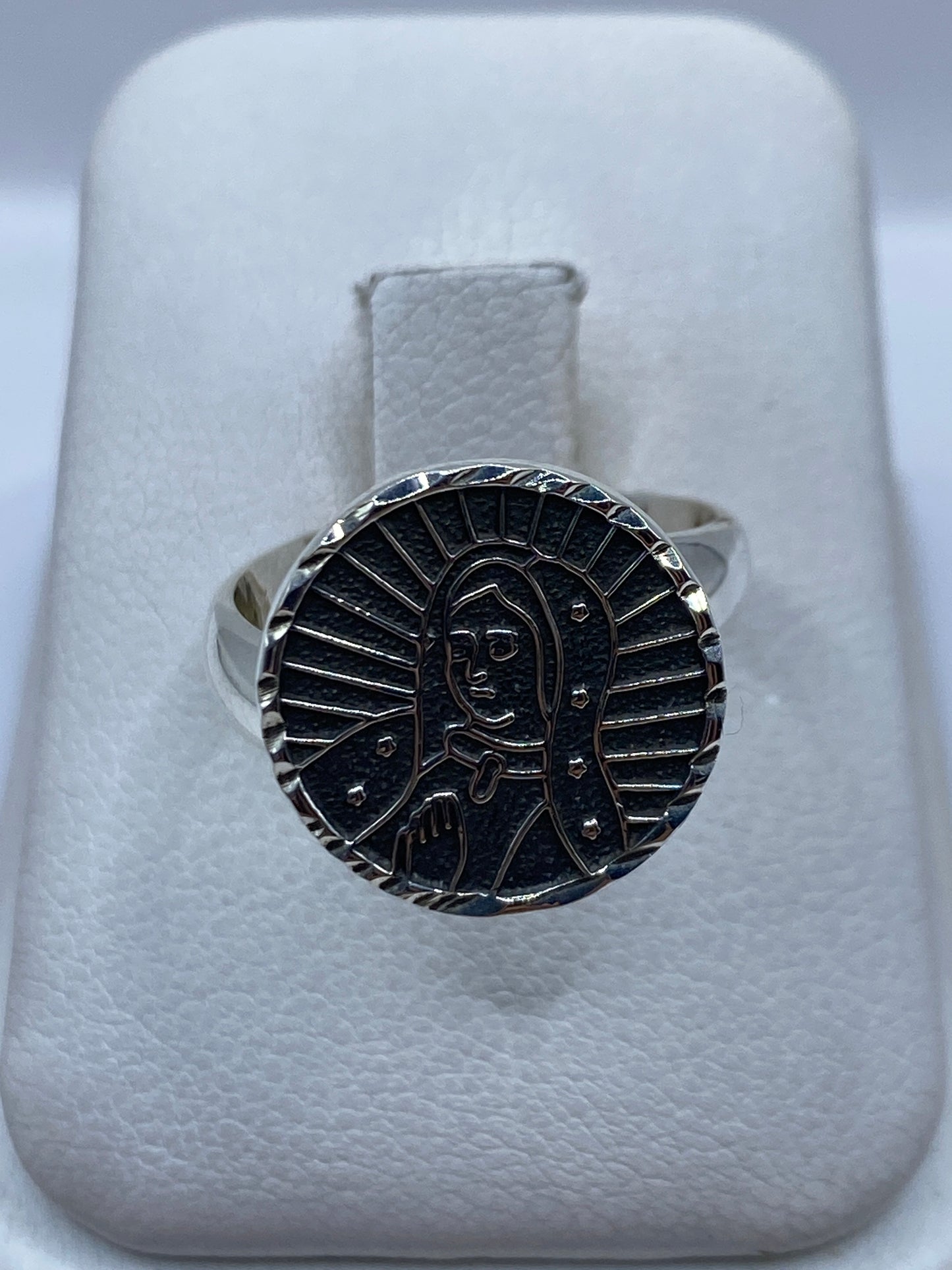 Anillo ajustable de plata .925 con grabado religioso en relieve, sobre dedo de mujer