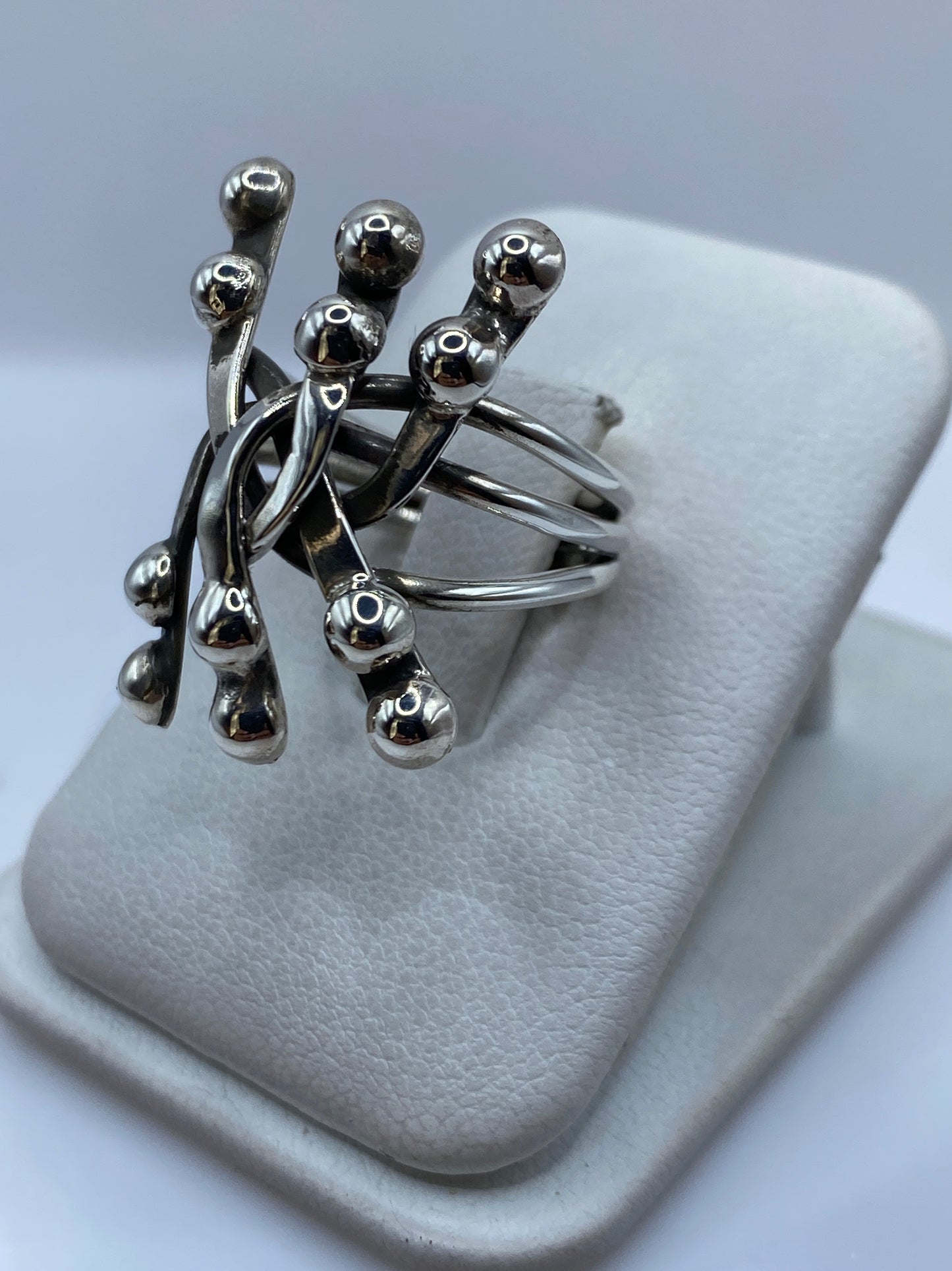 Detalle de las esferas de plata pulida reflejando luz, anillo sobre mano de mujer