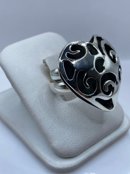 Vista frontal del anillo ajustable corazón calado sobre dedo de mujer