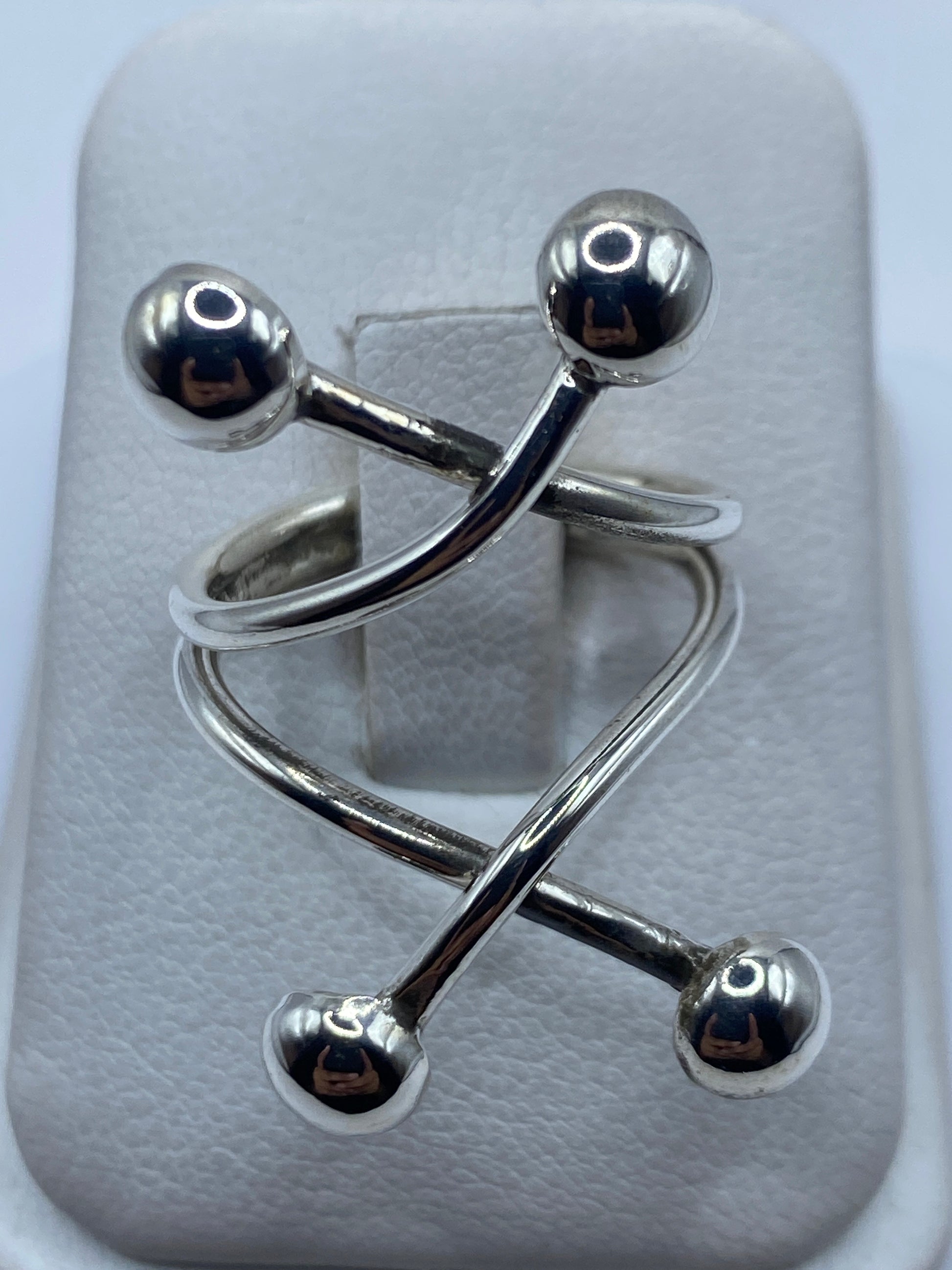 Anillo ajustable de plata .925 con eslabones y esferas sobre almohadilla blanca, vista superior